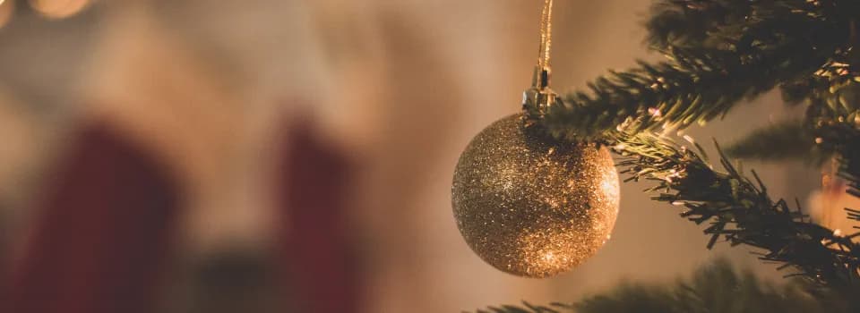 Golden Christmas ornament hanging on fir tree branch, symbolizing Christmas and Advent traditions in Sweden explained through festive decorations and warm candlelight.